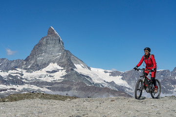 Fototapeta na wymiar active senior woman, riding her electric mountainbike below the famous Matterhorn in Zermatt, Wallis,Switzerland