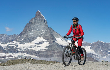 Fototapeta premium active senior woman, riding her electric mountainbike below the famous Matterhorn in Zermatt, Wallis,Switzerland