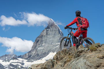 active senior woman, riding her electric mountainbike below the famous Matterhorn in Zermatt,...