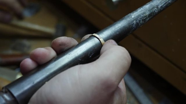 A goldsmith uses a ring mandrel to resize a gold ring
