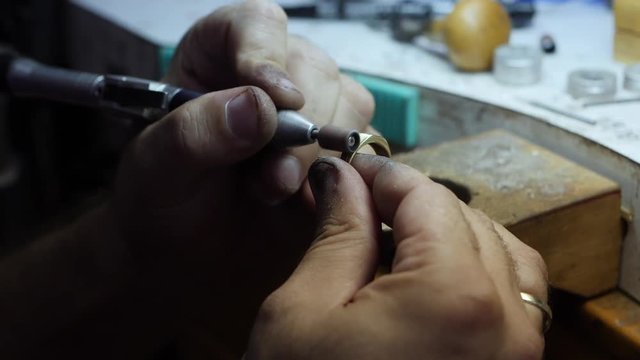 Close-up of using a dremel pin polisher to buff a gold ring