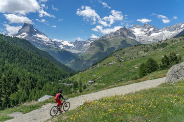 Fototapeta premium woman on mountain bike above the village of Findeln, high above of Zermatt, Vallais,Wallis, Switzerland, famous Mount Matterhorn in the background