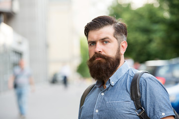 Naklejka premium Guy exploring city. Comfortable tourism. Summer vacation. Hipster wearing backpack urban street background. Bearded man travel with backpack. Sightseeing concept. Backpack for urban travelling