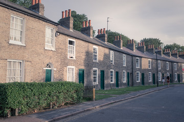 Row of restored Victorian brick houses with green colored doors and white windows.