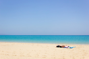 Fototapeta na wymiar Lonely woman sunbathing on empty beach. Female tourist enjoying summer holidays on paradise island with turquoise water sea. Travel vacation, unique destination concepts