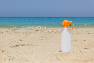 Bright white sunscreen spray on sand by turquoise water sea. Summer holidays, vacation on paradise, lotion bottle, skin care protection concepts