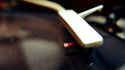 Stylus on a vintage turntable playing a vinyl music record, close-up shot.