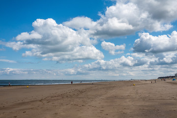 Knokke-Heist, Flanders, Belgium -  June 16, 2019: Knokke-Zoute part of town. View from sandy beach on LNG sea terminal and Wind turbines of Port of Zeebrugge. People on sand. Greenish Nord Sea,