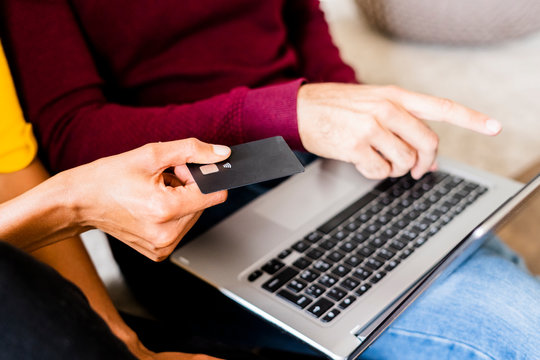 Close-up of couple at home shopping online with laptop and credit card