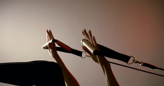 Close-up of the hands and feet of a sports girl, she is engaged in Pilates, doing exercises with the help of a simulator on her hands and feet.