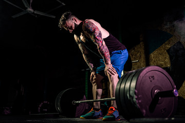 Muscular fitness man preparing to deadlift a barbell over his head in modern fitness center....