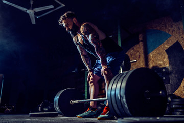 Muscular fitness man preparing to deadlift a barbell over his head in modern fitness center....
