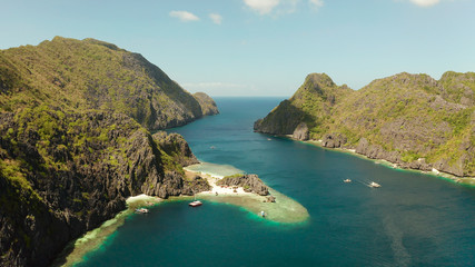 Tropical lagoon with sandy beach surrounded by cliffs, aerial view. El nido, Philippines, Palawan. Seascape with tropical rocky islands, ocean blue water. Summer and travel vacation concept