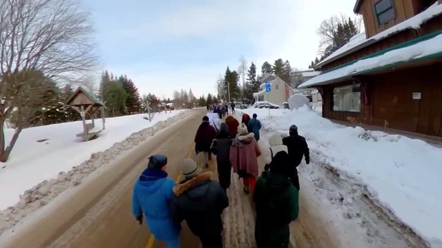 Activists march during ecological rally. High angle footage on a group of ecological campaigners marching through a snowy town during winter. People wearing padded coats unite against global warming.