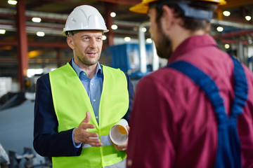 The foreman gives instructions to the engineer at the factory.