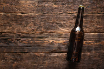 Beer bottle on a brown wooden table flat lay background with a copy space.