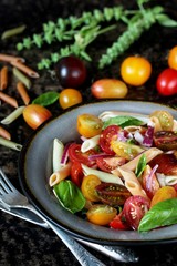 pasta salad with cherry tomatoes of different colors, colored pasta and basil. bright summer salad.