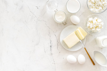 Fresh dairy products for breakfast with milk, cottage, eggs, butter, yougurt on white marble background top view mock up