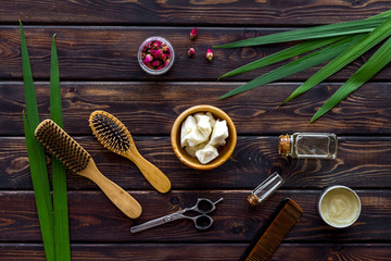 Natural oil for hair near bottles and brush on wooden background top view pattern