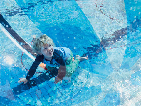 Portrait of little boy having fun with beach ball and swimming pool