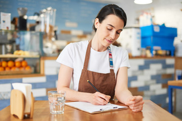 Barista makes notes in the notepad about the menu