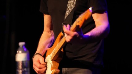 Traditional folk music played in bar. Close-up shots of a young guy playing an electronic guitar inside a local establishment by night, details of skilled hands at work.