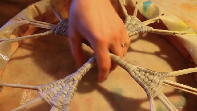 Hands of an artisan making sacred drum. Close up footage of an artisan at work on a native drum. Stretching and tying the rawhide membrane over a wood frame.