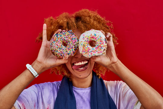 Playful woman holding two donuts in front of her eyes