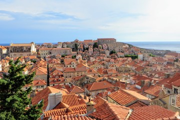 Fototapeta na wymiar A full view of the old town in Dubronvik Croatia from the perspective of the walls of Dubronvik. The old town is all old homes with clay tiled roofs and the beautiful adriatic sea is in the background