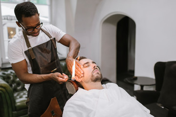 Barber removing ear hair of a customer with fire in barber shop