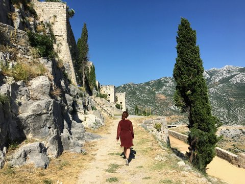 A young female tourist walking around the medieval fortress of Klis on a beautiful summer day.The Klis Fortress is  situated above a village bearing the same name, near Split, Croatia.