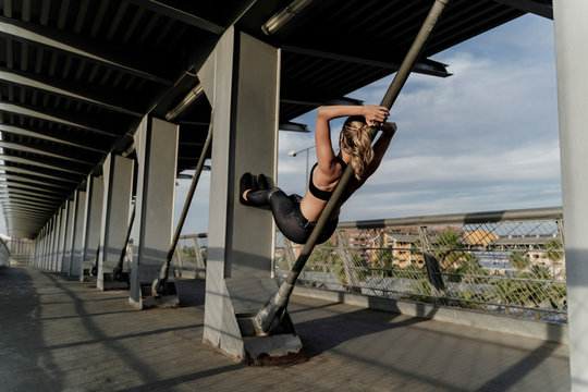 Sporty woman working out o a bridge, leaning on bar