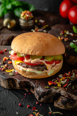 Tasty grilled burger with with beef, cheese, vegetables.  Delicious grilled Cheeseburger on a dark background. Free space for text