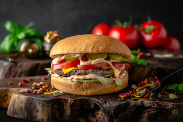 Tasty grilled burger with with beef, cheese, vegetables.  Delicious grilled Cheeseburger on a dark background. Free space for text