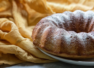 Pumpkin cake on a white dish on yellow fabric. 