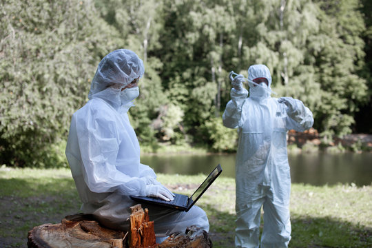Ecological problem. Pollution. Examine oxygen. Scientist in protective mask and suit taking water samples from river. Chemist makes an analysis of the environment for radiation. 