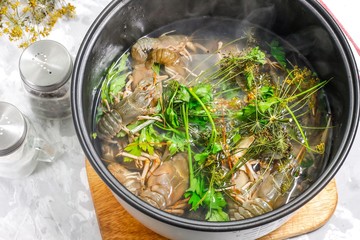Fresh crayfish in a bowl of the cooker in boiling water with spices and herbs - the ingredients for cooking boiled crayfish in a slow cooker. Step 6.