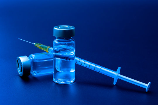 Vaccines, botulinum toxin and insulin ampules concept theme with glass vials with clear liquid next to a syringe and a hypodermic needle isolated on black background