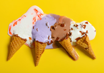 top view multiple flavor ice cream cones melted on yellow background