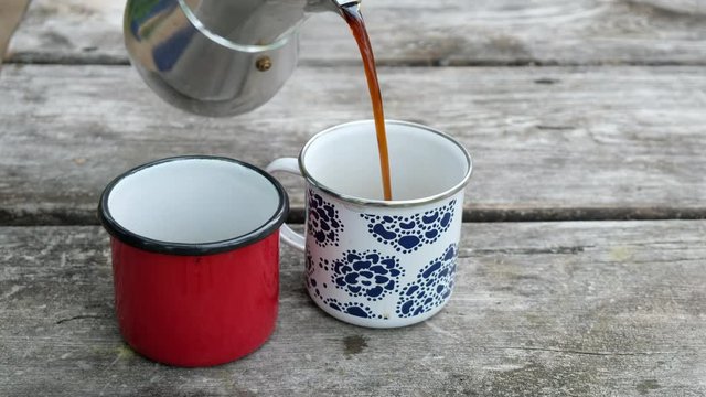 Pouring coffee into cup on rustic table, camping