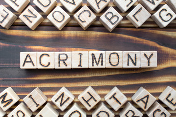 acrimony wooden cubes with letters, bitter full of anger concept, around the cubes random letters,...