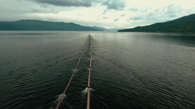 Aerial Drone Shot of Canadian Logging Tug Boat Pulling Logs & Timber Through Shuswap Lake, British Columbia, Canada. Logging Industry Forestry 