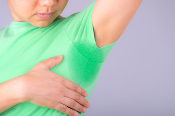 Close-up young women with hyperhidrosis sweating. Young  woman with sweat stain on her clothes against grey background. Healthcare concept.