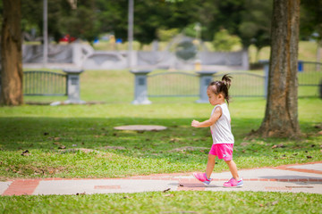 Fototapeta premium Asian toddler girl running in the park at the spring or summer day.