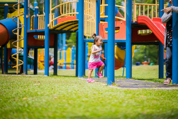 Fototapeta na wymiar Adorable little 1-2 year old Asian toddler girl having fun on playground.