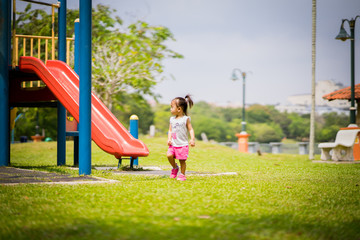 Adorable little 1-2 year old Asian toddler girl having fun on playground.
