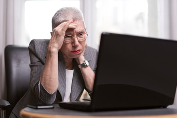 Disturbed elderly businesswoman receiving very bad news in her email