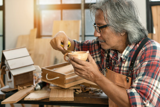 asian senior carpenter concentrating to his woodwork in workshop as hobby