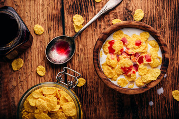 Breakfast with corn flakes, milk and berry syrup