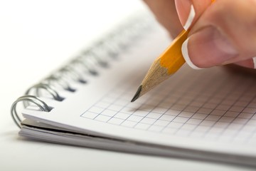 Closeup of a Person Writing on Notepad